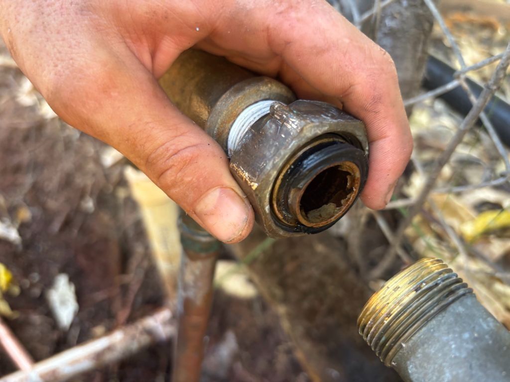 A Person is Holding a Brass Pipe in Their Hand — Nightcliff Plumbing & Gas In Coconut Grove, NT