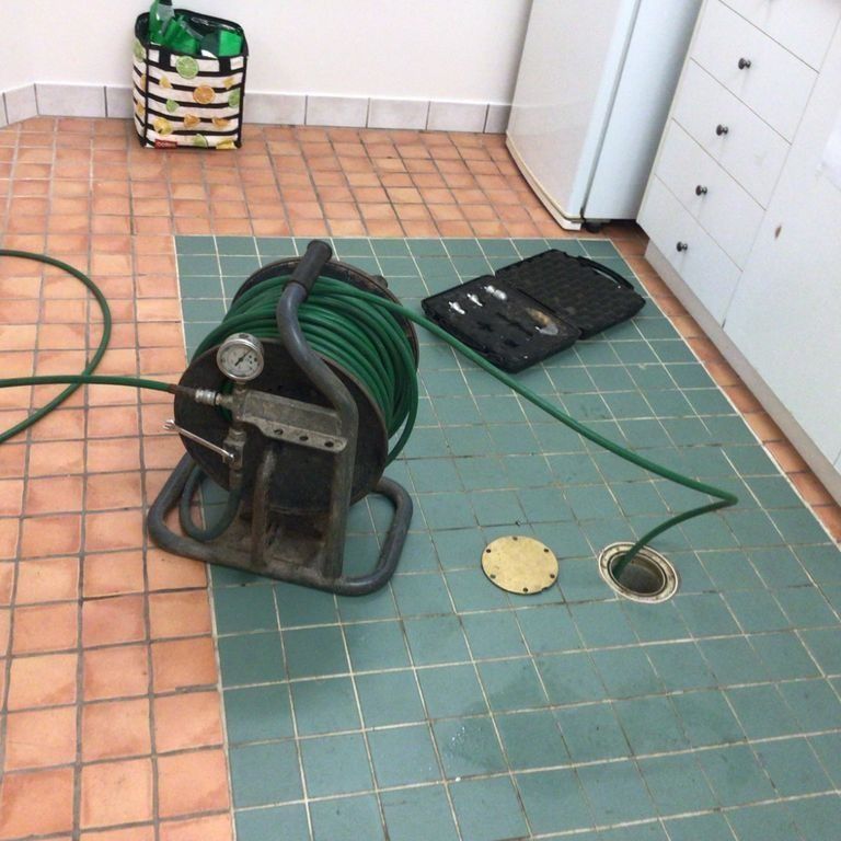 A Green Hose is Laying on a Tiled Floor — Nightcliff Plumbing & Gas In Parap, NT