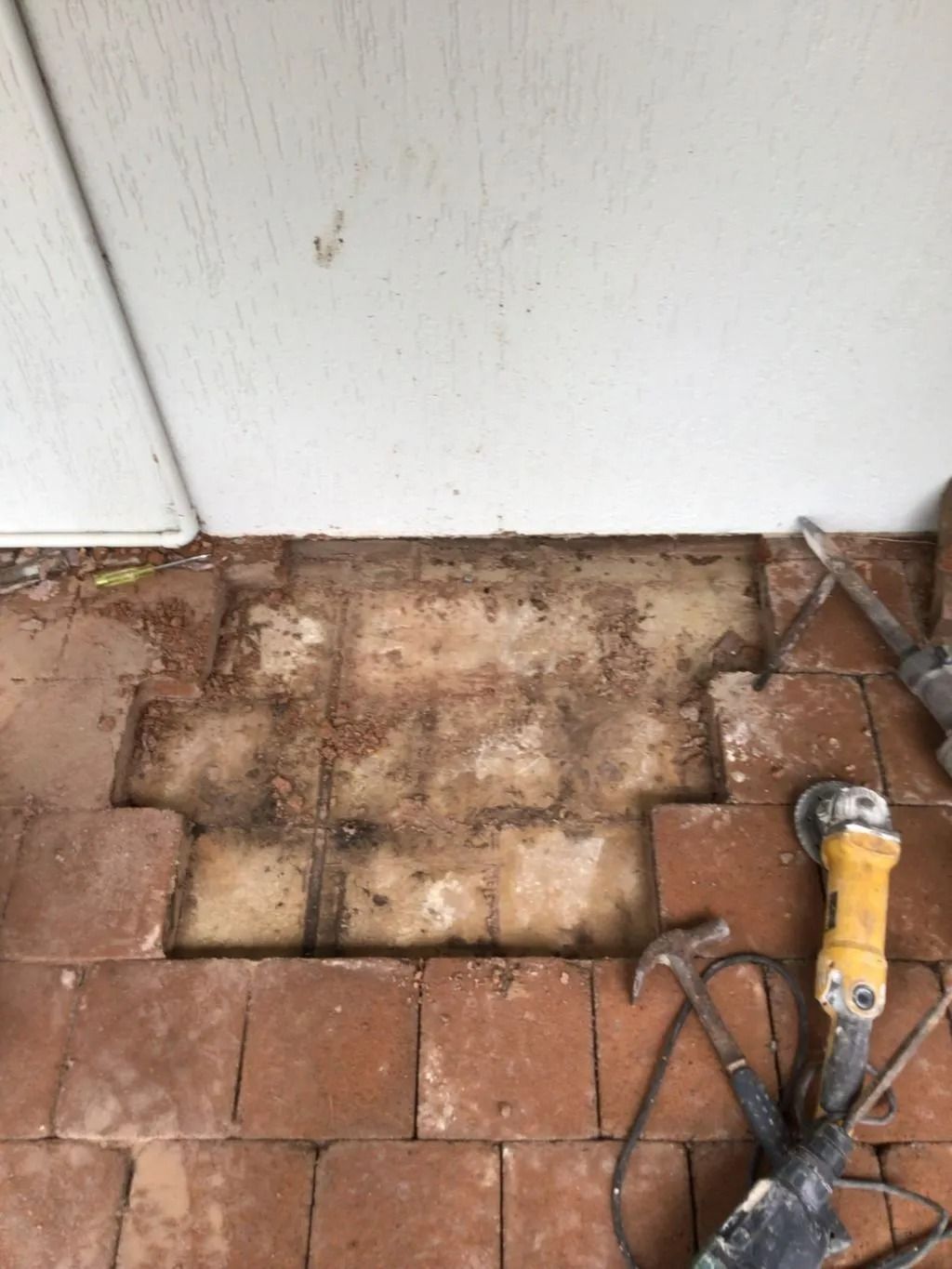 A Brick Floor With a Hammer and a Grinder on It — Nightcliff Plumbing & Gas In Coconut Grove, NT