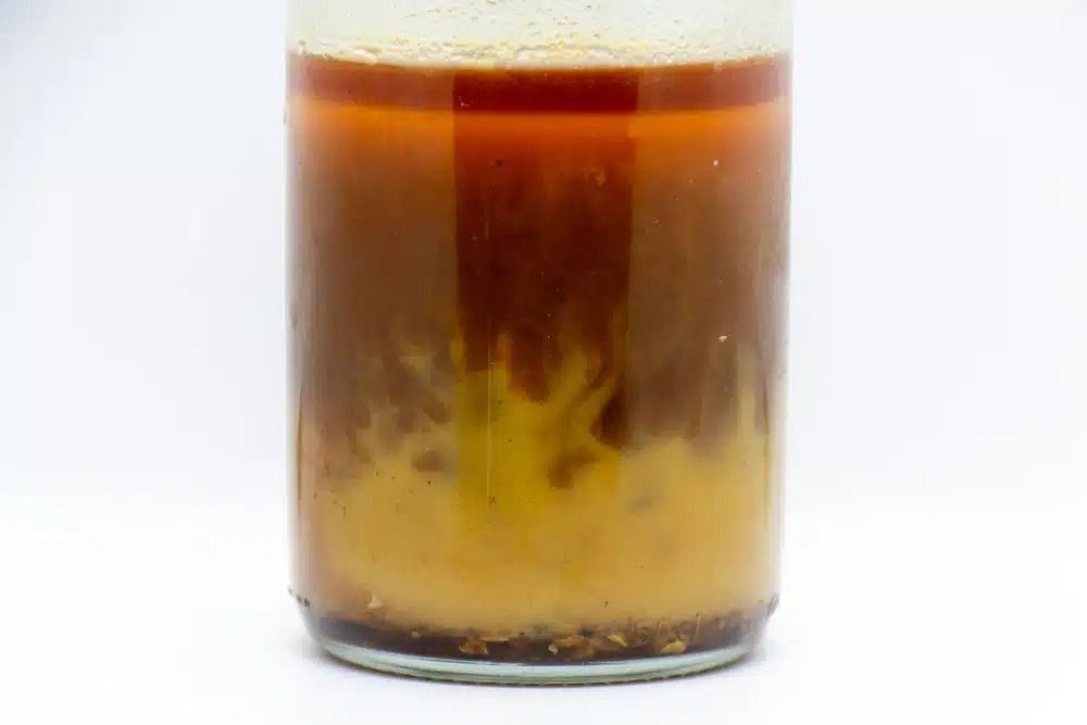 A Glass Filled With Brown Liquid on a White Background — Nightcliff Plumbing & Gas In Coconut Grove, NT