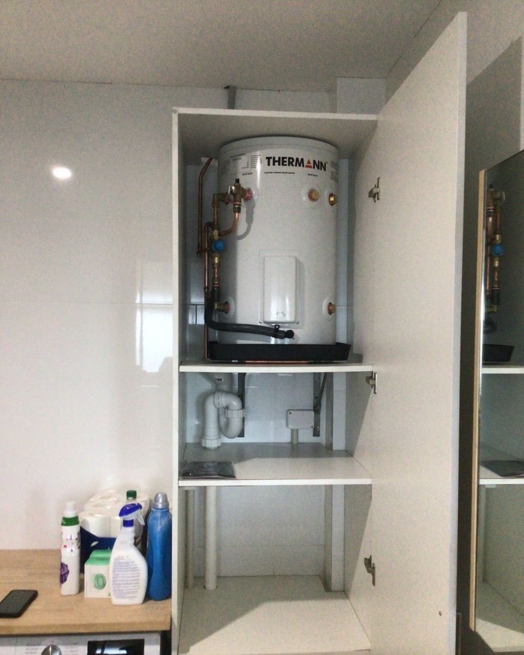 A White Water Heater in a Cabinet With the Door Open — Nightcliff Plumbing & Gas In Coconut Grove, NT