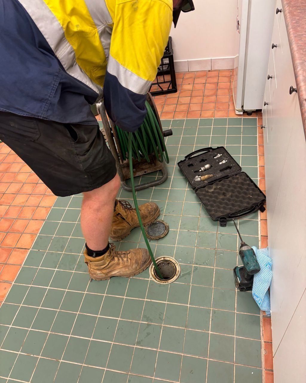 A Man is Working on a Drain in a Kitchen — Nightcliff Plumbing & Gas In Coconut Grove, NT