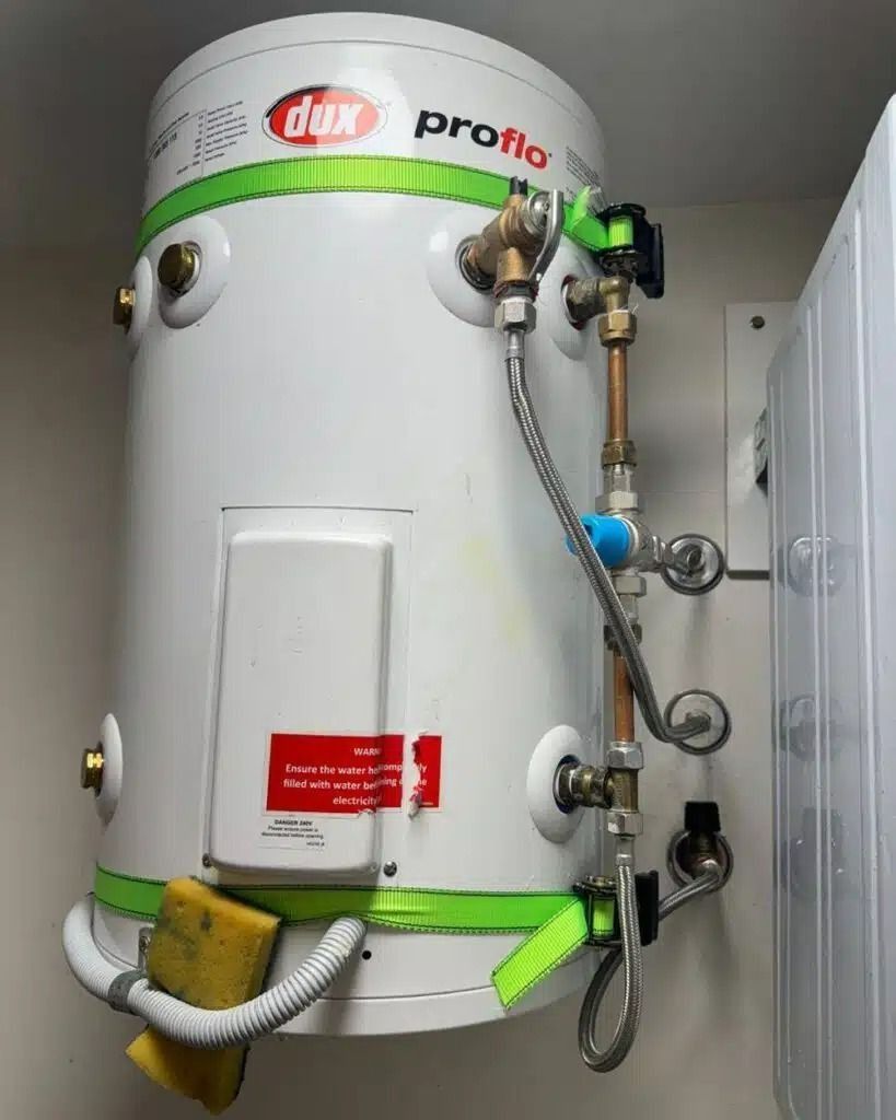 A White Water Heater is Hanging on a Wall Next to a Washer and Dryer — Nightcliff Plumbing & Gas In Coconut Grove, NT