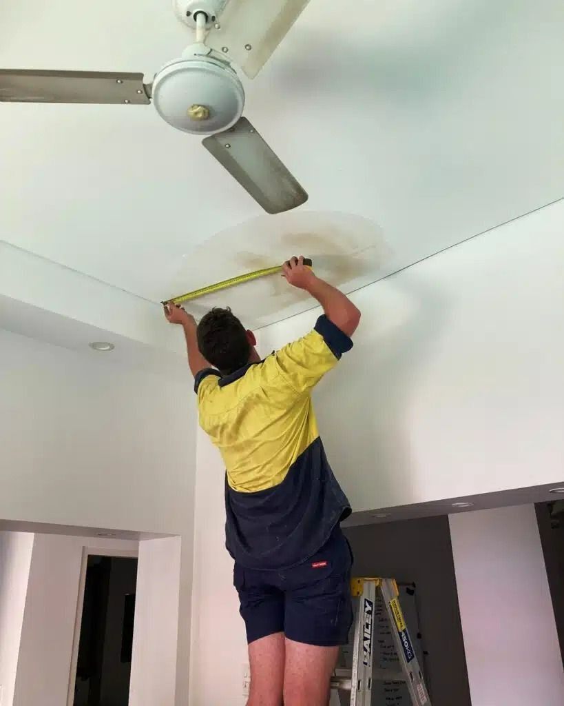 A Man is Measuring the Ceiling With a Tape Measure — Nightcliff Plumbing & Gas In Coconut Grove, NT