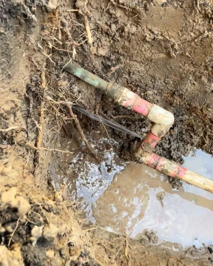 A Muddy Pipe is Sitting in the Dirt Next to a Puddle of Water — Nightcliff Plumbing & Gas In Coconut Grove, NT