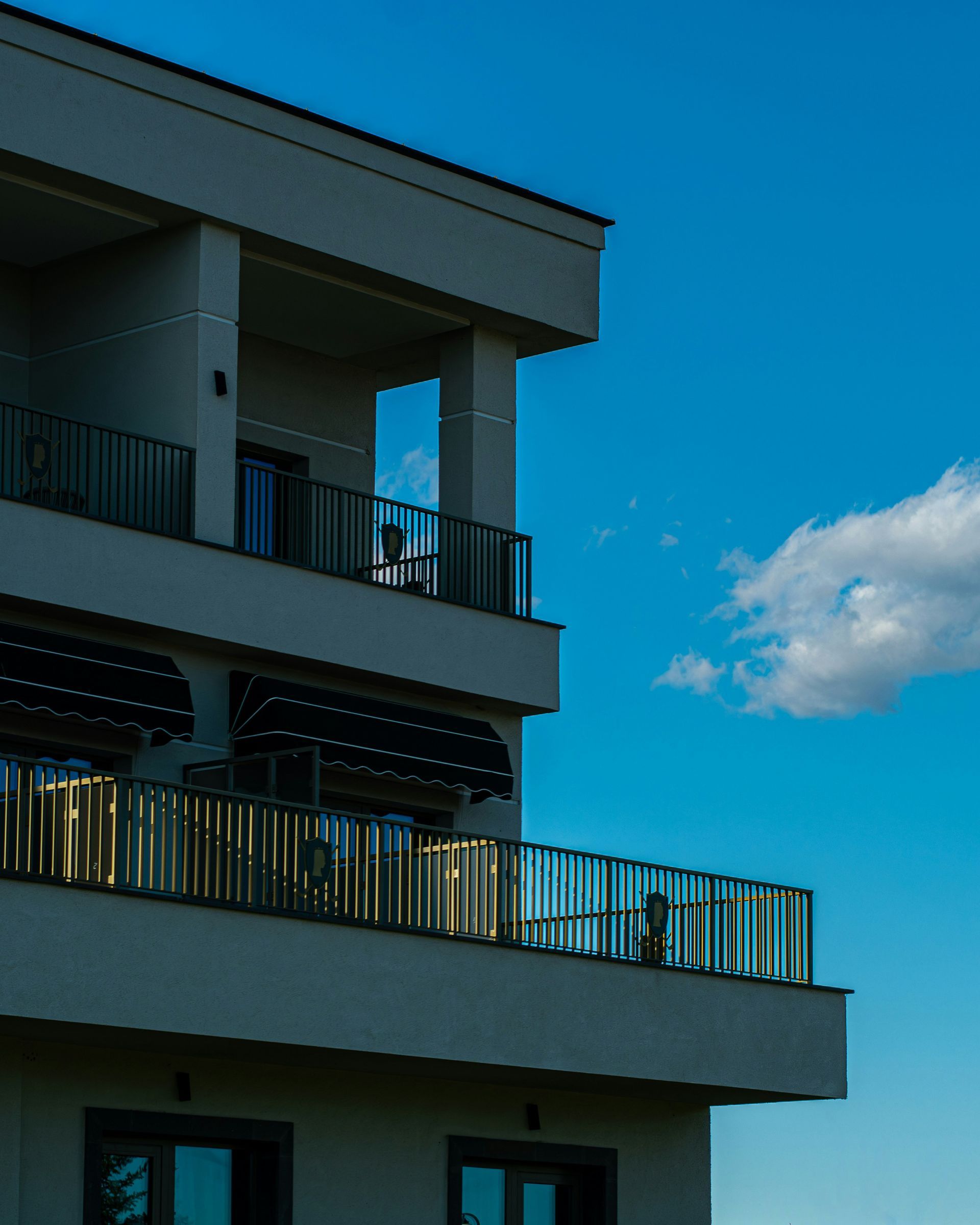 Modern apartment balcony against a bright blue sky with a small cloud