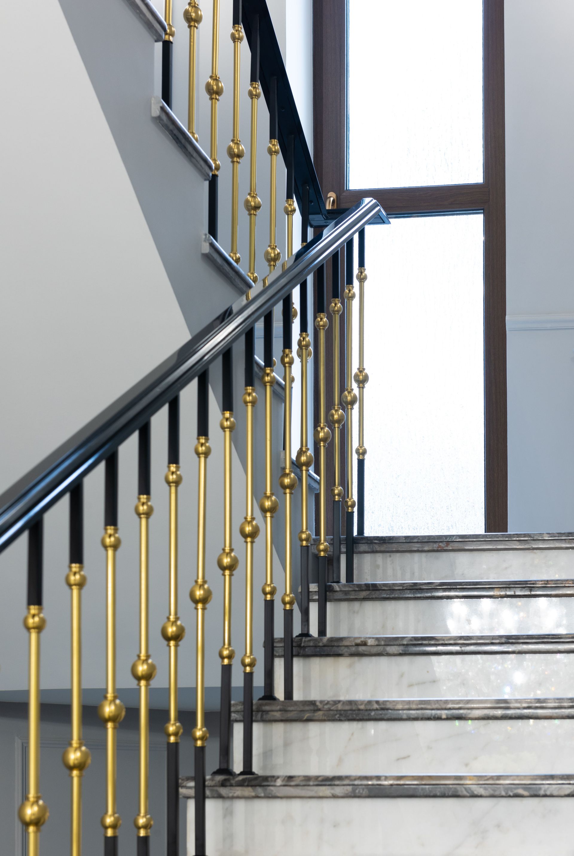 Staircase with black and gold railing beside a bright window