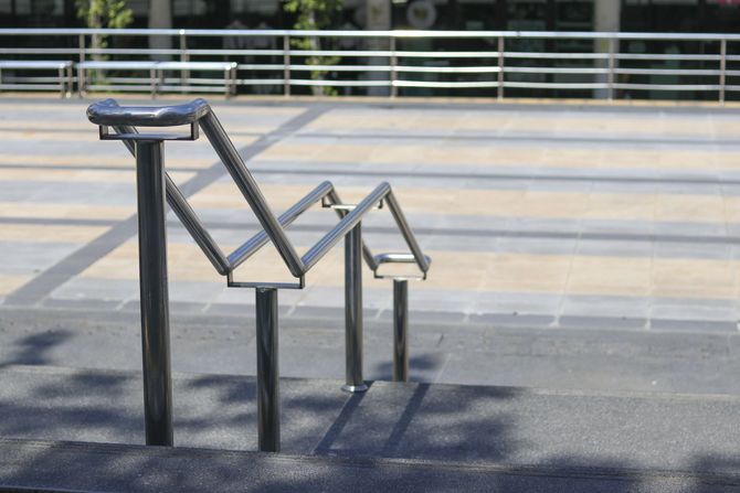A metal handrail along concrete stairs in an outdoor plaza.