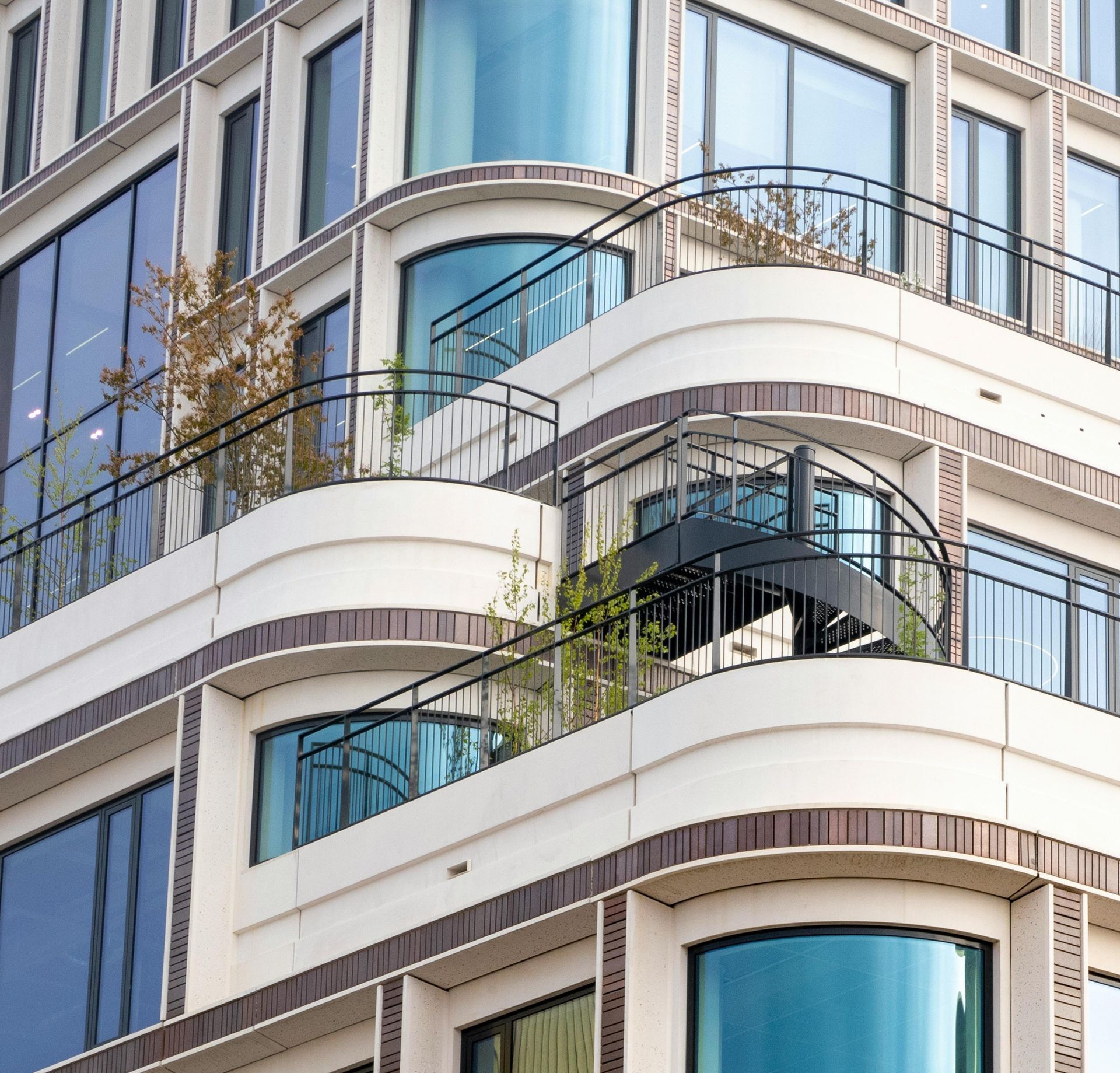 Curved white Milpitas apartment balconies with blue-tinted glass and black railings on a modern building.