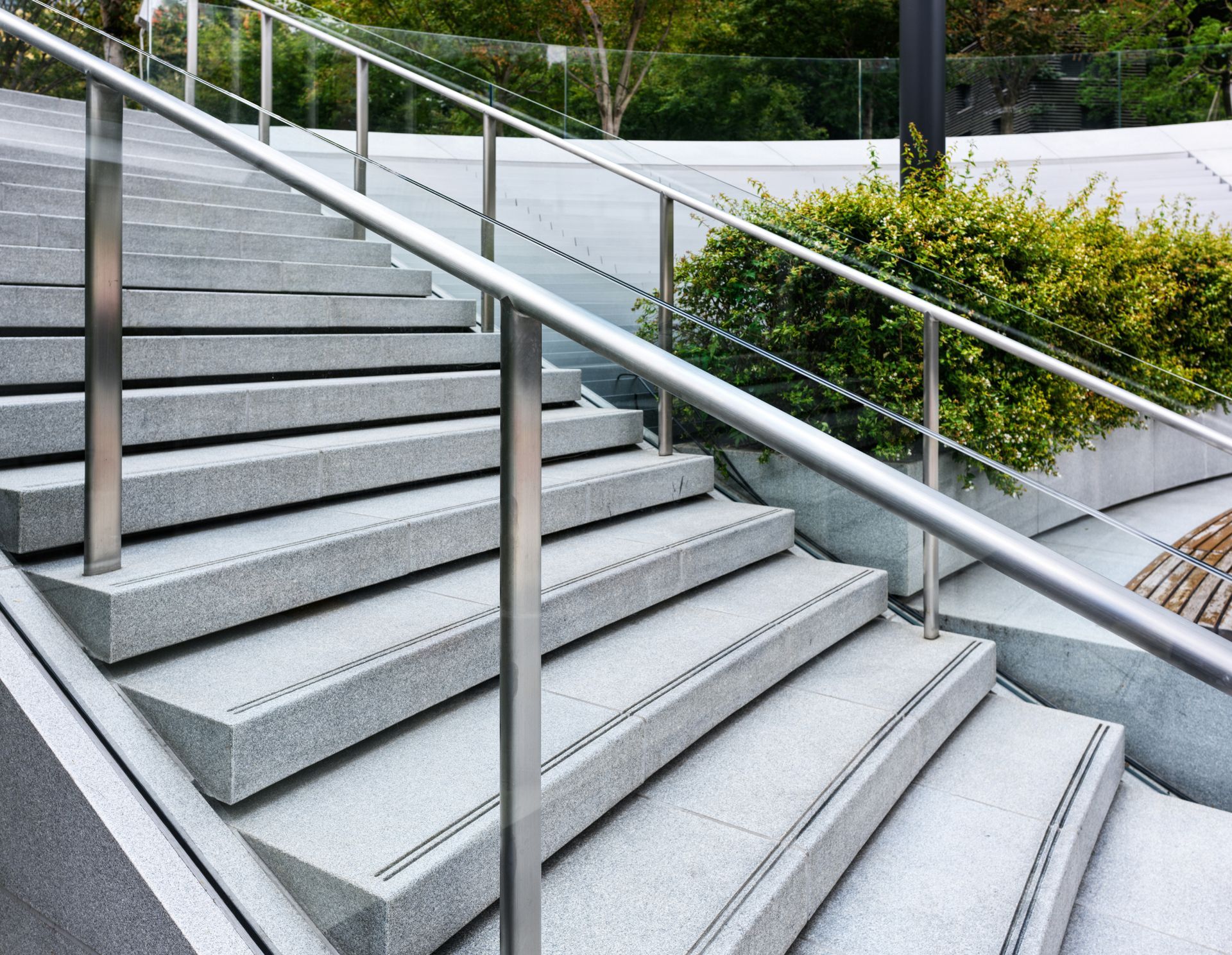 Outdoor concrete stairs with metal railings and landscaped greenery beside them