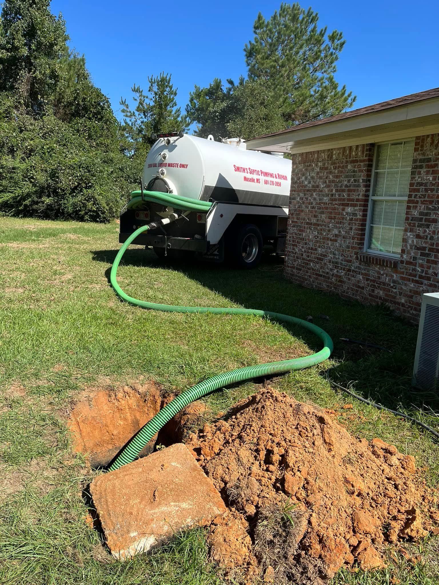 A septic tank truck is pumping water into a hole in the ground.