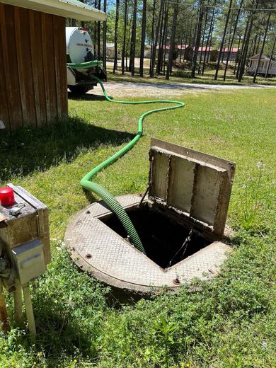 A septic tank with the lid open and a green hose coming out of it.