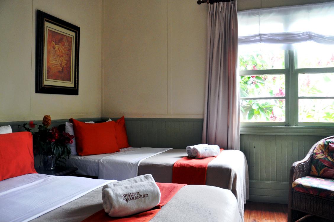 Cozy bedroom with two beds, red accents, a window, and daylight