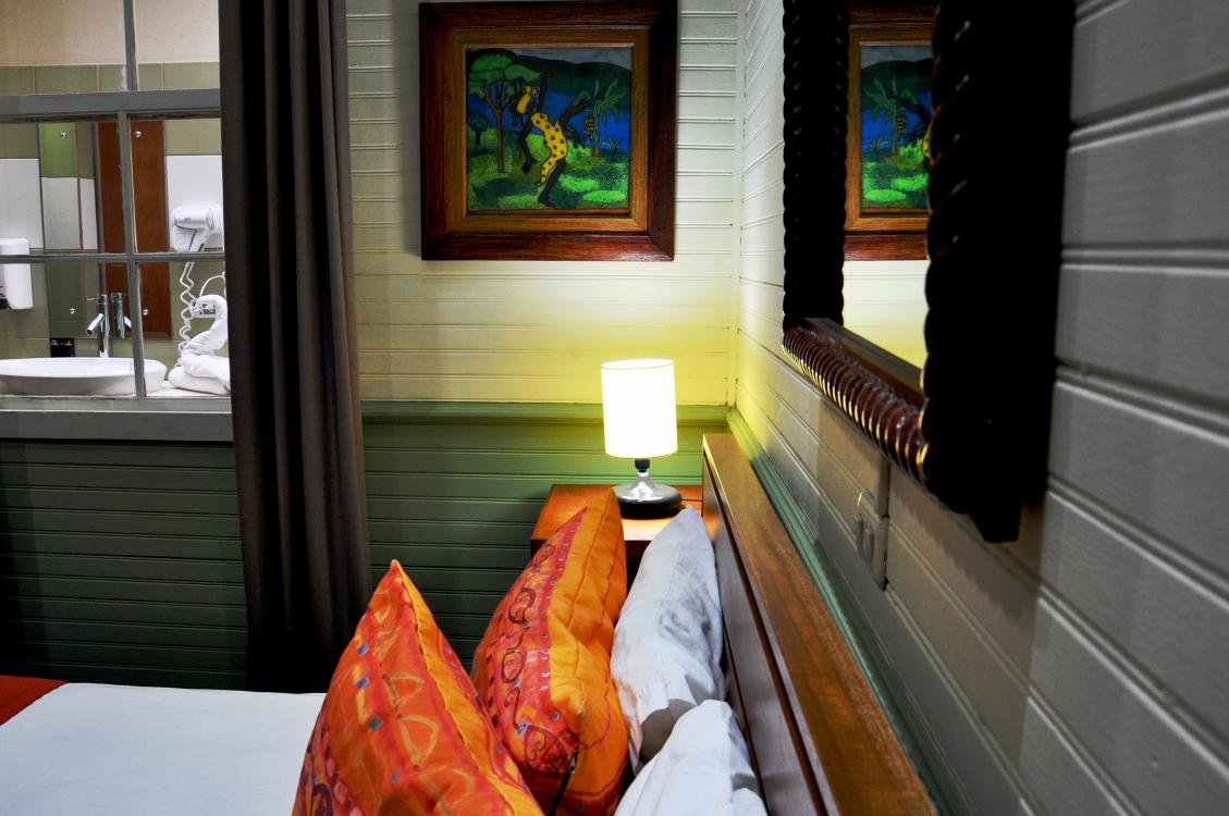 Cozy bedroom with orange pillows, lit bedside lamp, framed art, and window with snow outside