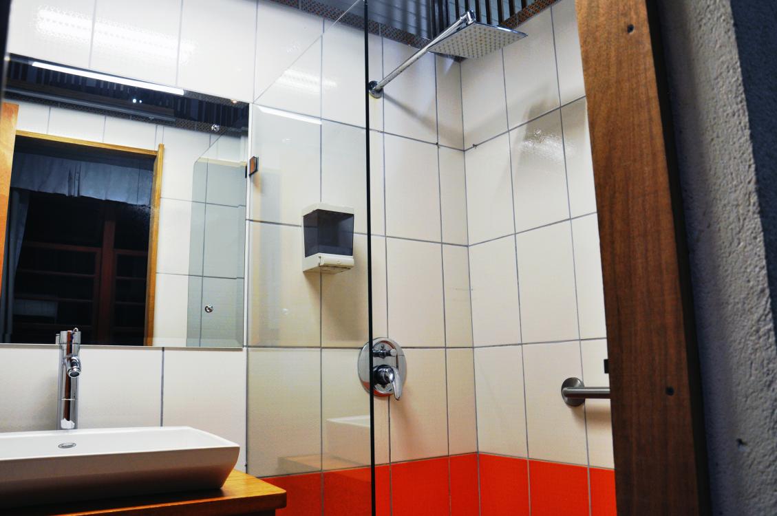 Modern bathroom with sink, mirror, glass shower, and cream-and-orange tiled walls