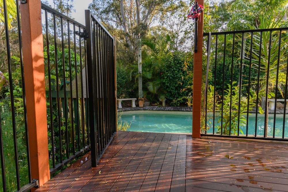 A Fence Surrounds a Large Swimming Pool in A Backyard — Topline Aluminium Forster Pty Ltd in Hallidays Point, NSW