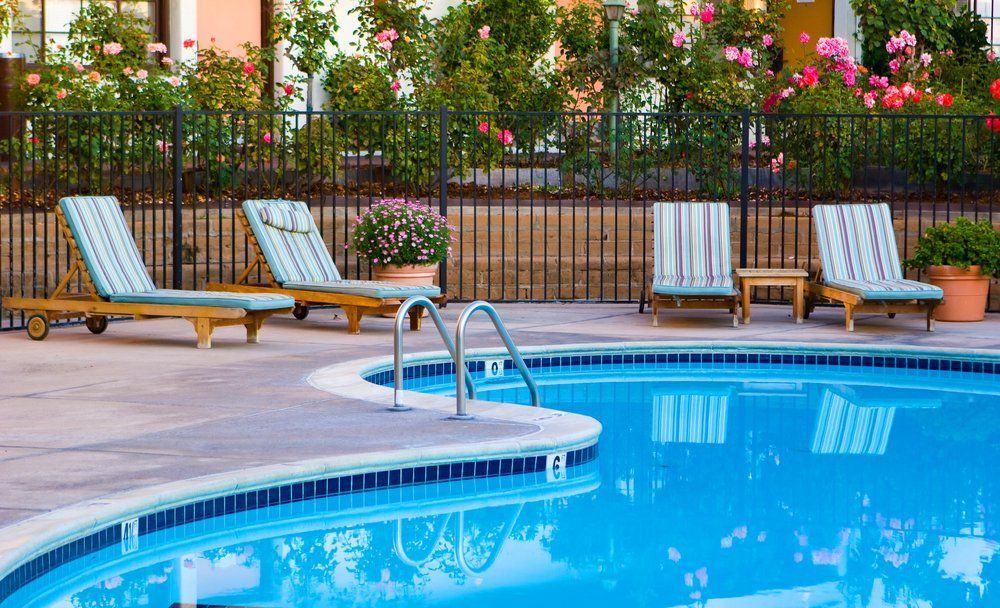 A Large Swimming Pool Surrounded by Chairs and A Fence — Topline Aluminium Forster Pty Ltd in Taree, NSW