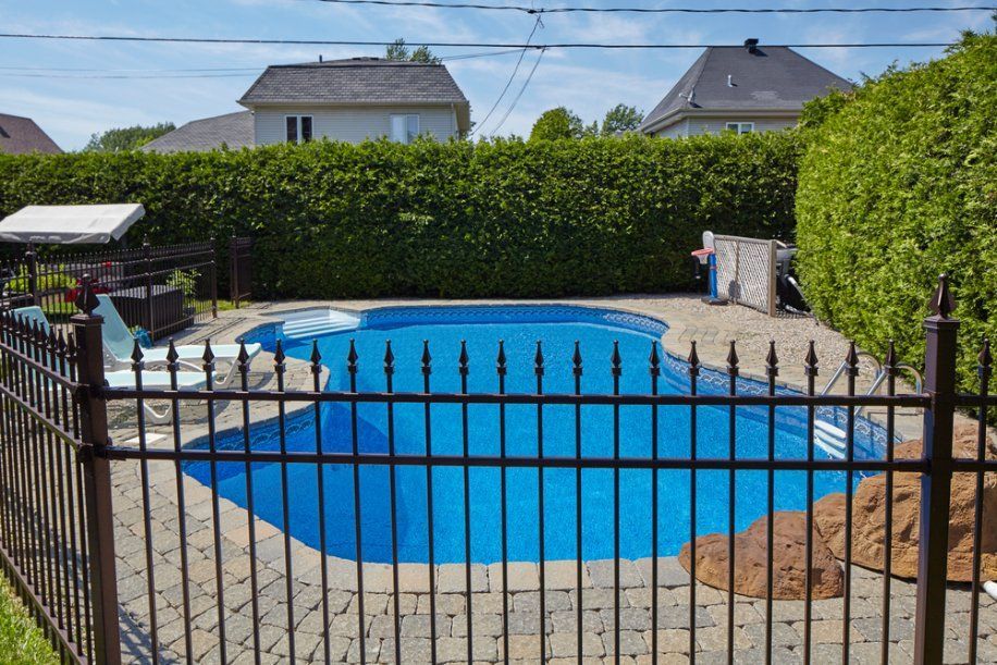 A Fence Surrounds a Large Swimming Pool in A Backyard — Topline Aluminium Forster Pty Ltd in Forster, NSW