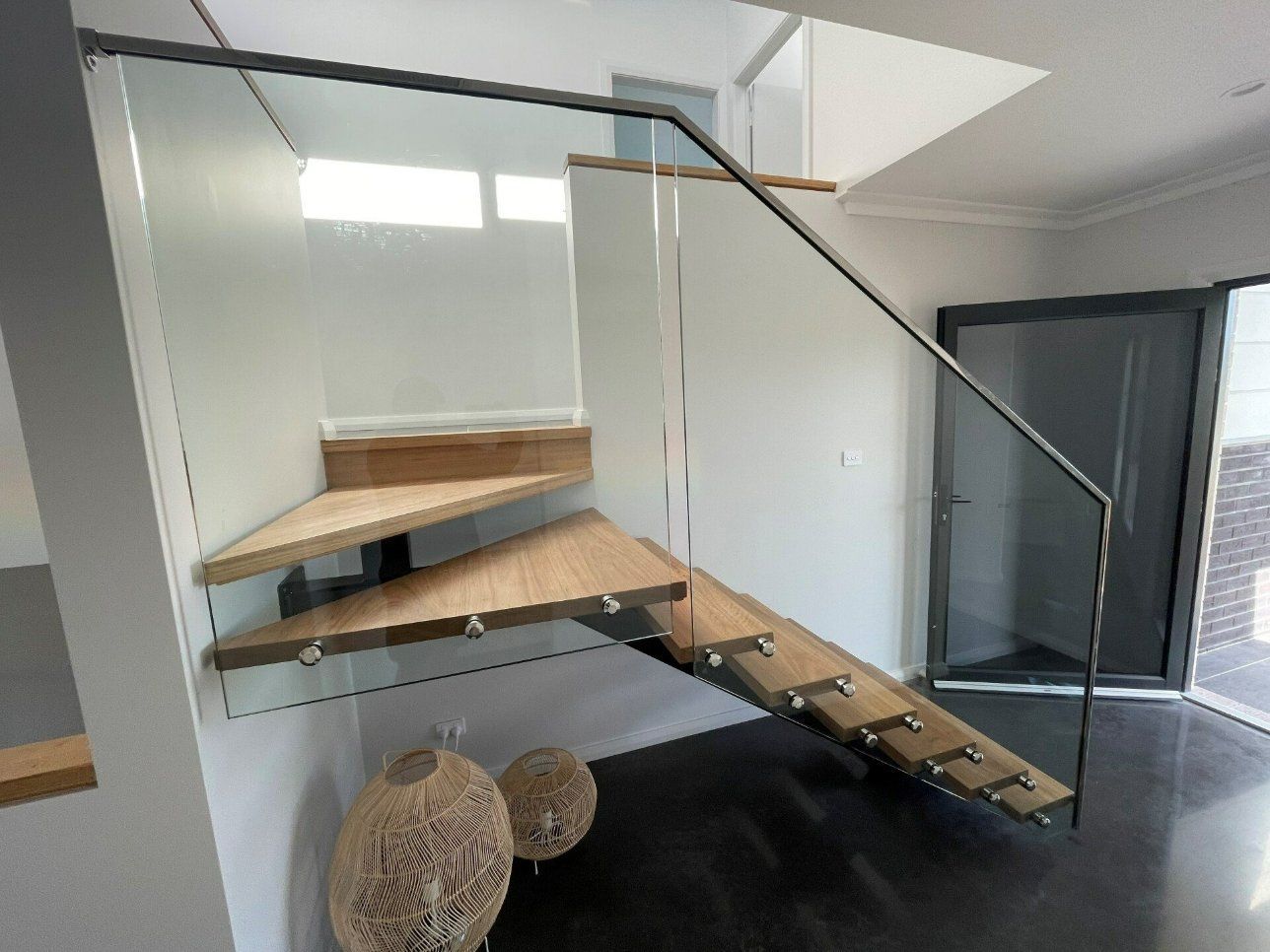 A Wooden Staircase with A Glass Railing in A Room — Topline Aluminium Forster Pty Ltd in Forster, NSW