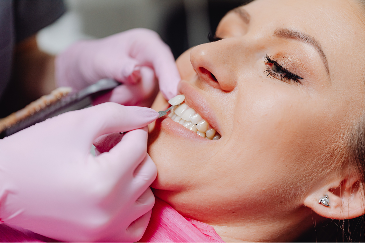 Dentist adjusting a woman’s teeth with pink gloves during a dental procedure