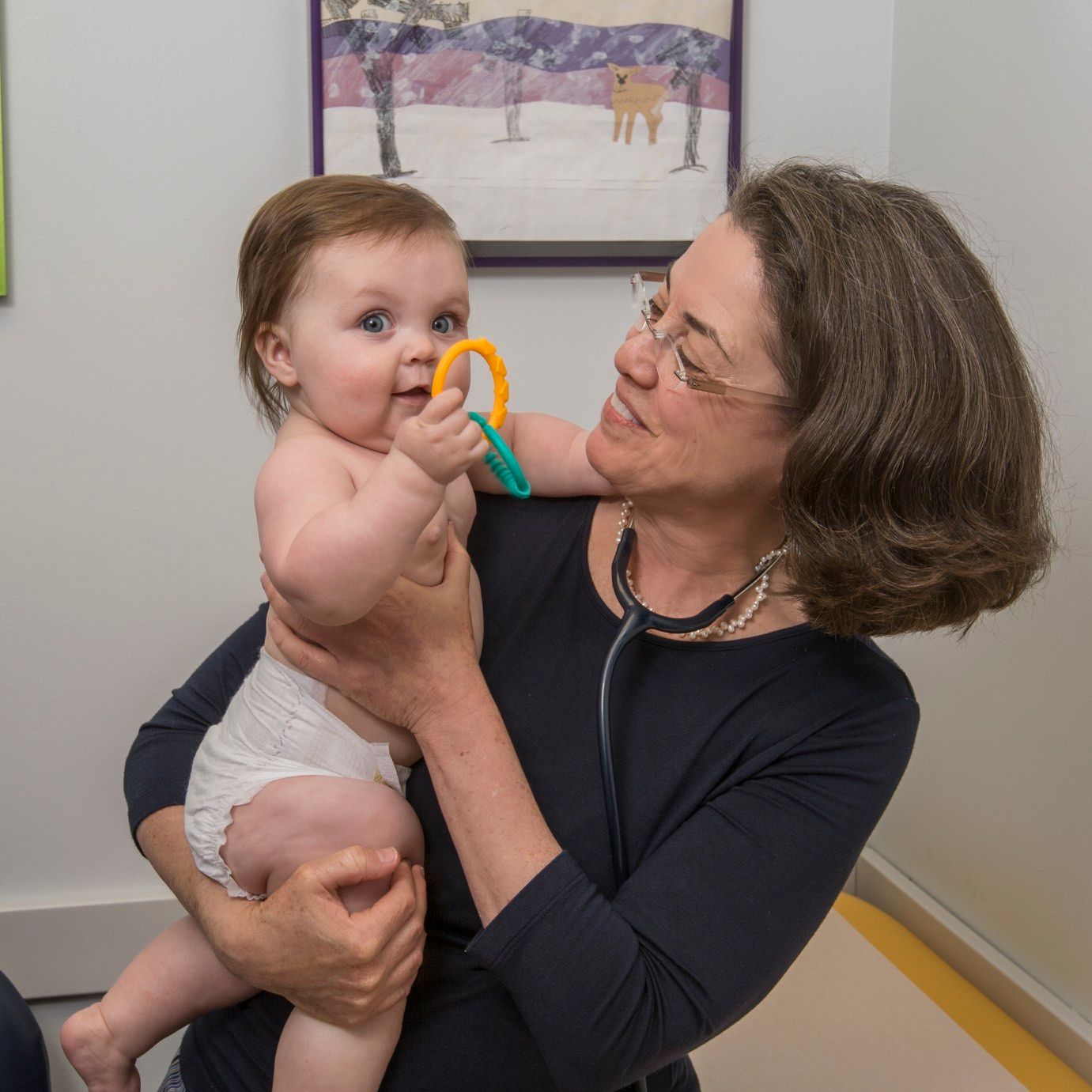 A woman is holding a baby with a stethoscope around her neck