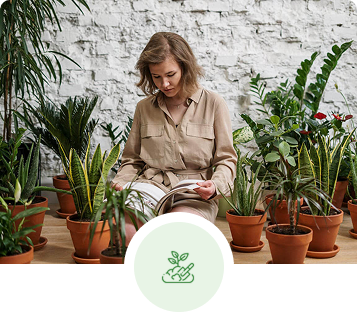 Woman reading surrounded by potted plants; light-colored brick background, and green icon of a hand holding a sprout.