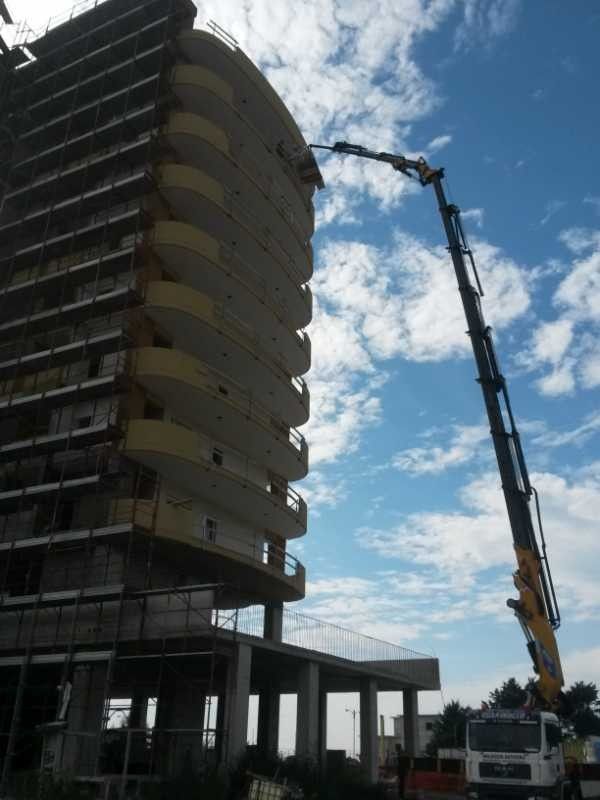 Gru da costruzione accanto a un grattacielo parzialmente eretto con solai e impalcature a vista.