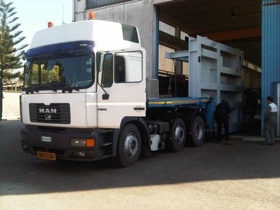 Camion cargo MAN bianco parcheggiato accanto alla banchina di carico di un magazzino.