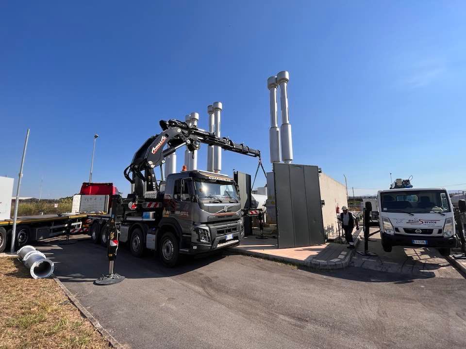 Camion di macchinari pesanti in un cantiere stradale sotto un cielo azzurro e limpido.