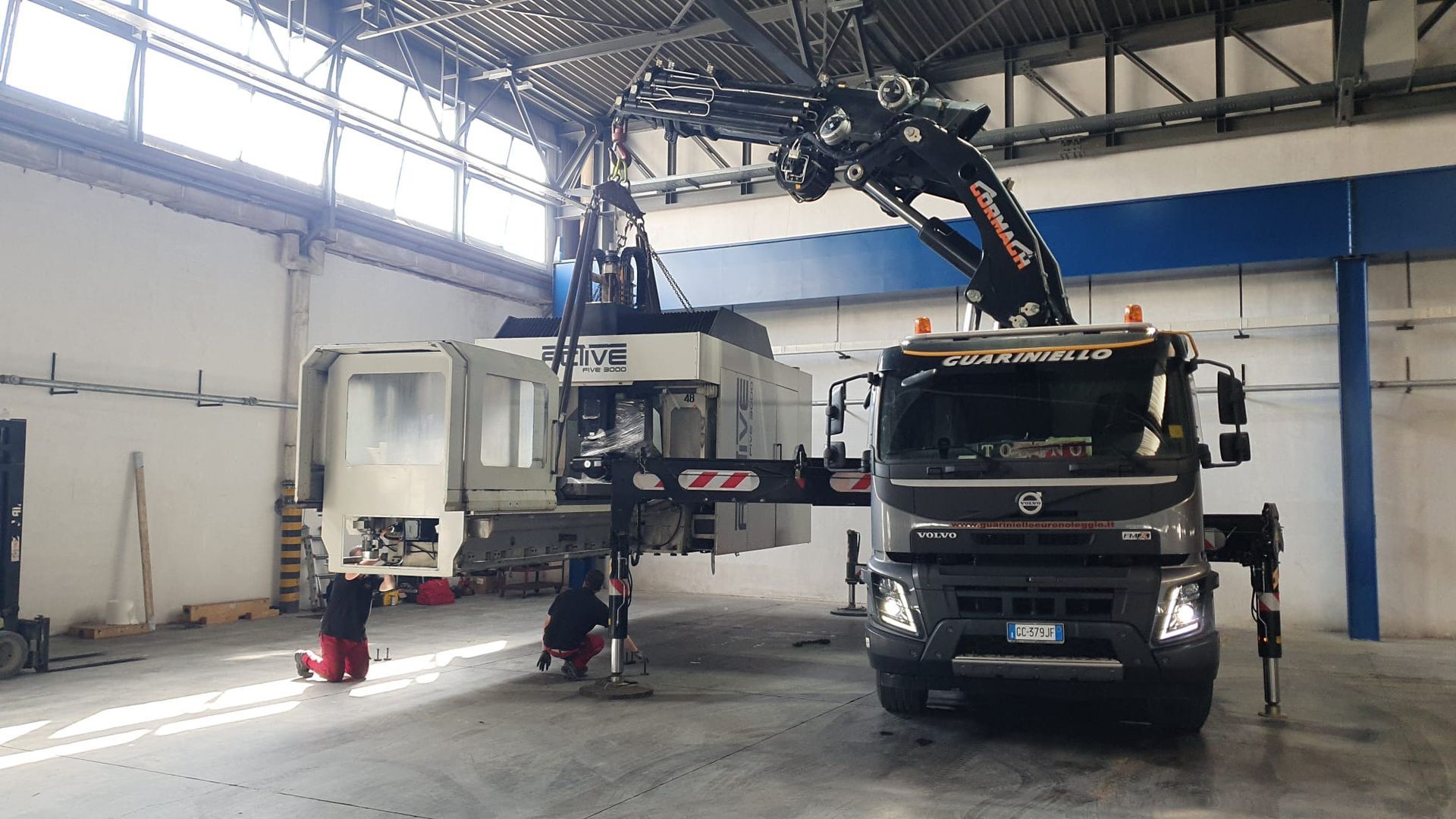 Un camion in un garage con due piattaforme aeree in funzione su un lato.