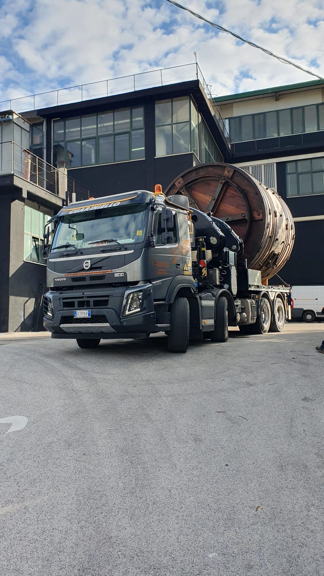 Un camion betoniera nero è parcheggiato davanti a un edificio moderno con ampie finestre.