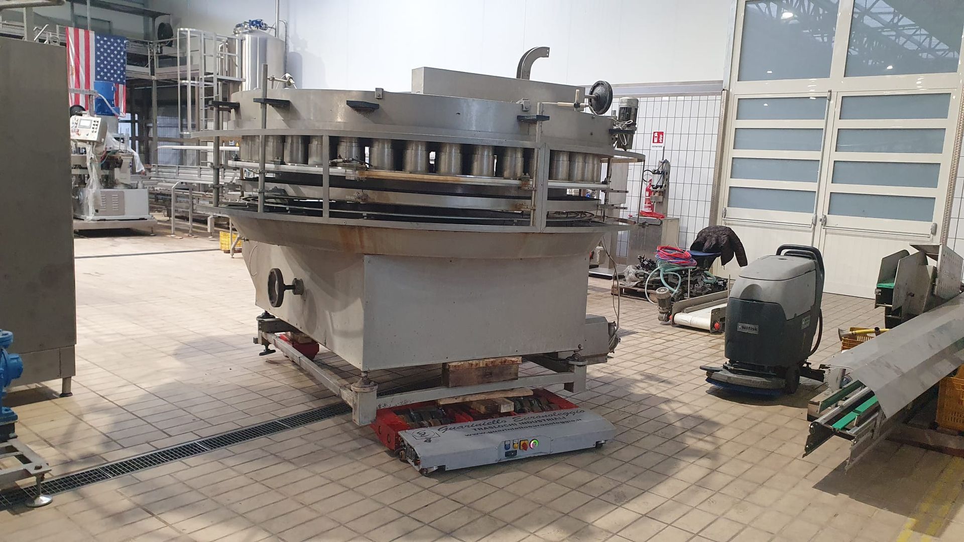 In un'officina, un grande macchinario industriale con parti metalliche e utensili su un pavimento piastrellato.