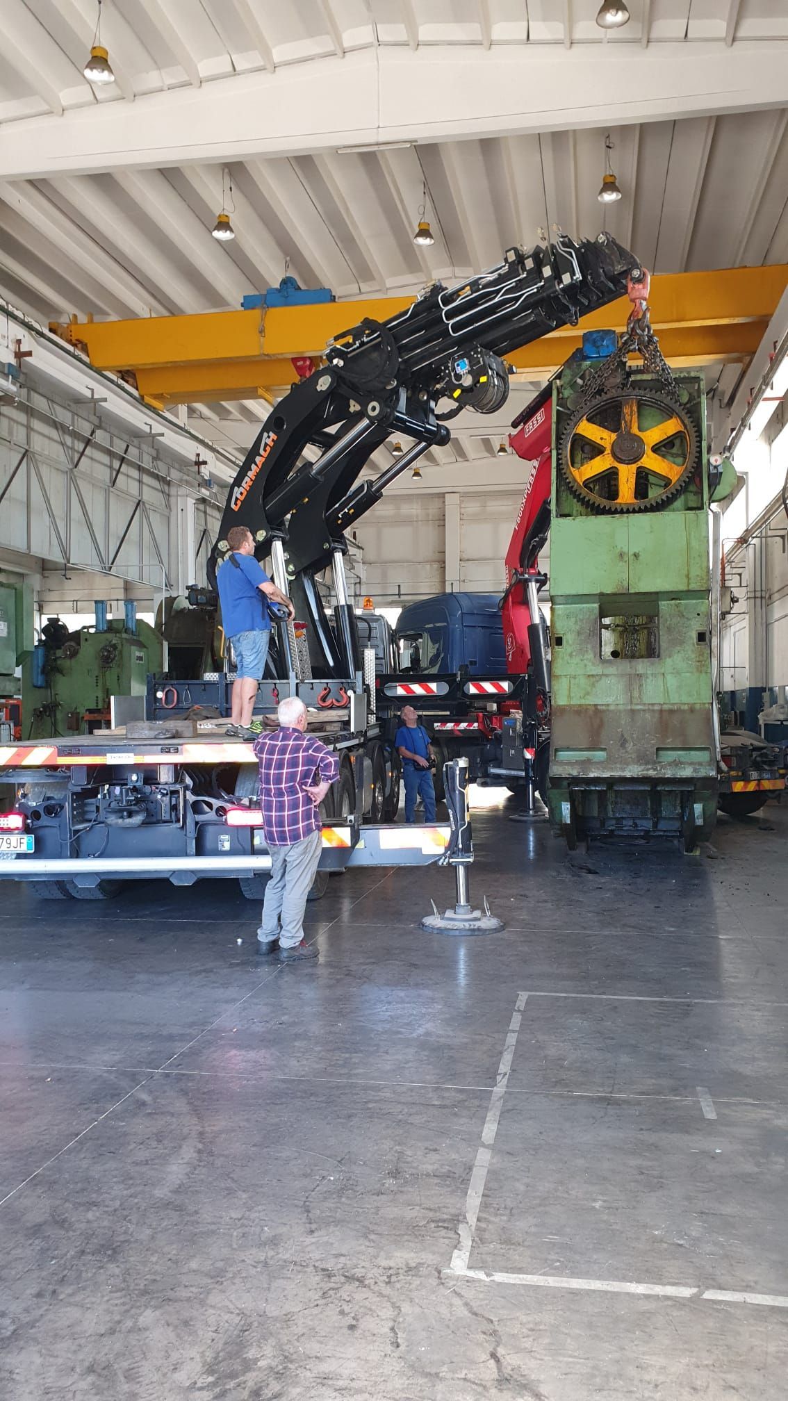 Due operai ispezionano dei macchinari sotto la grande ala di un aereo in un hangar.
