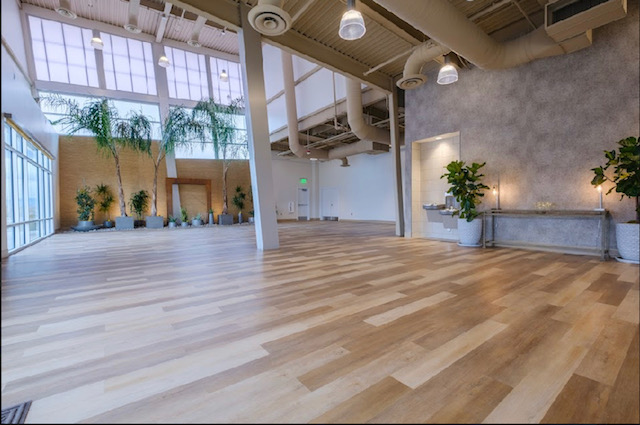 A large empty room with a wooden floor and lots of windows.