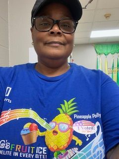 Person in blue shirt with pineapple graphic and glasses, looking at the camera.