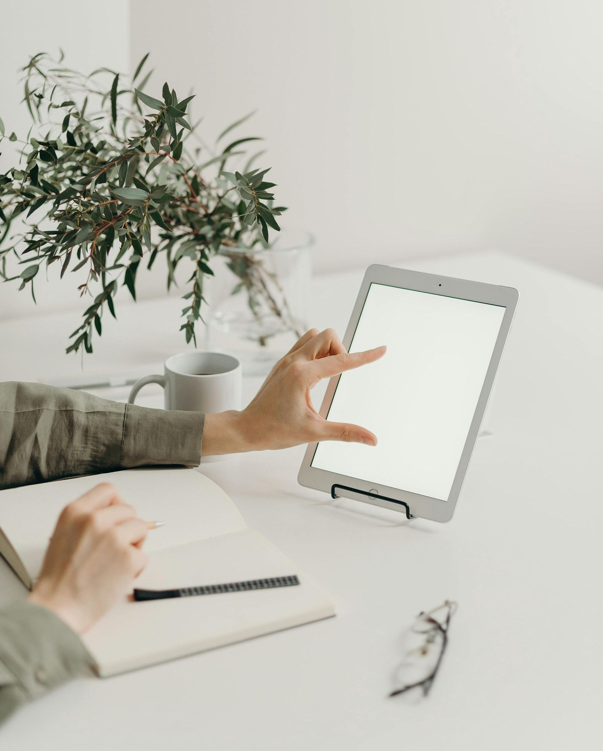 A person is sitting at a table using a tablet computer.