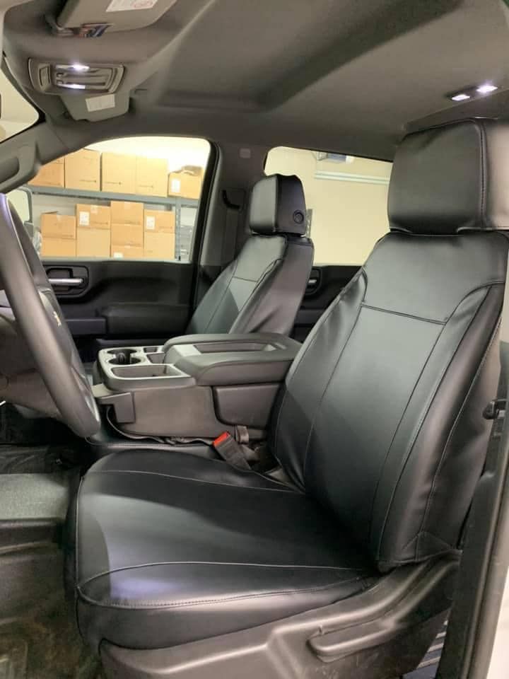 Black leather car interior with front seats, center console, and open rear door in a showroom-like setting