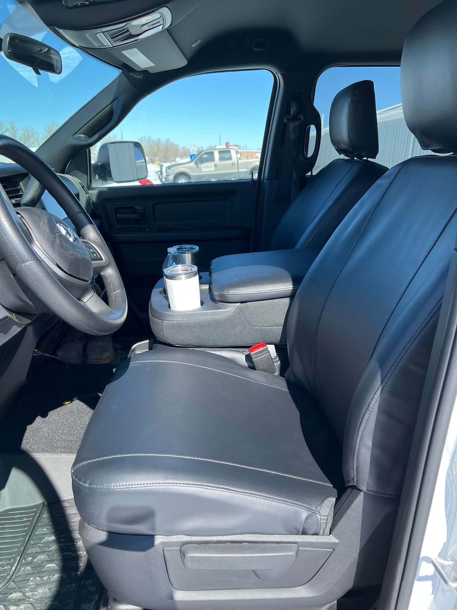 Car interior with black leather seats and steering wheel, plus a water bottle in the center console.