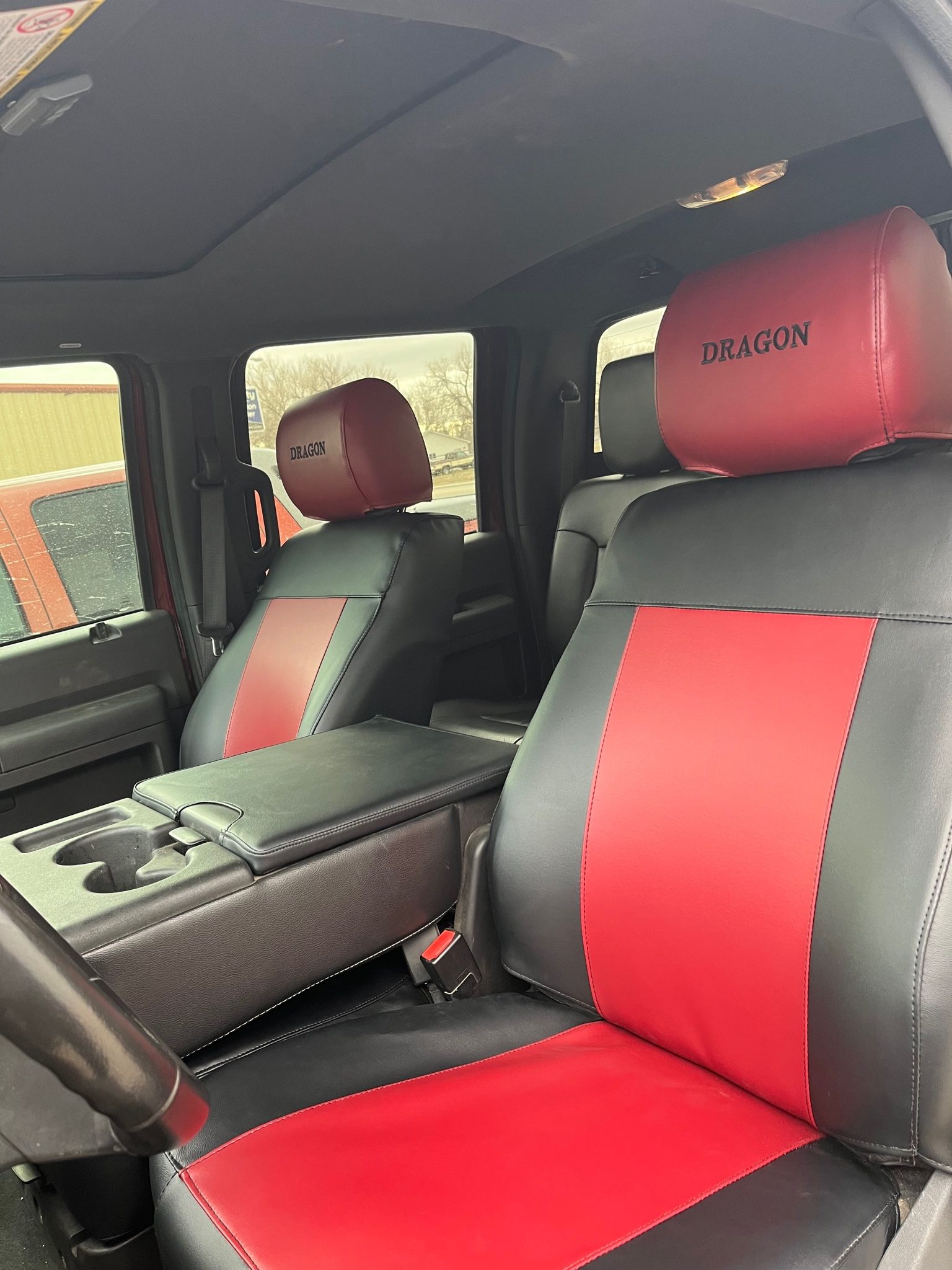 Car interior with red-and-black seats, center console, and steering wheel visible.