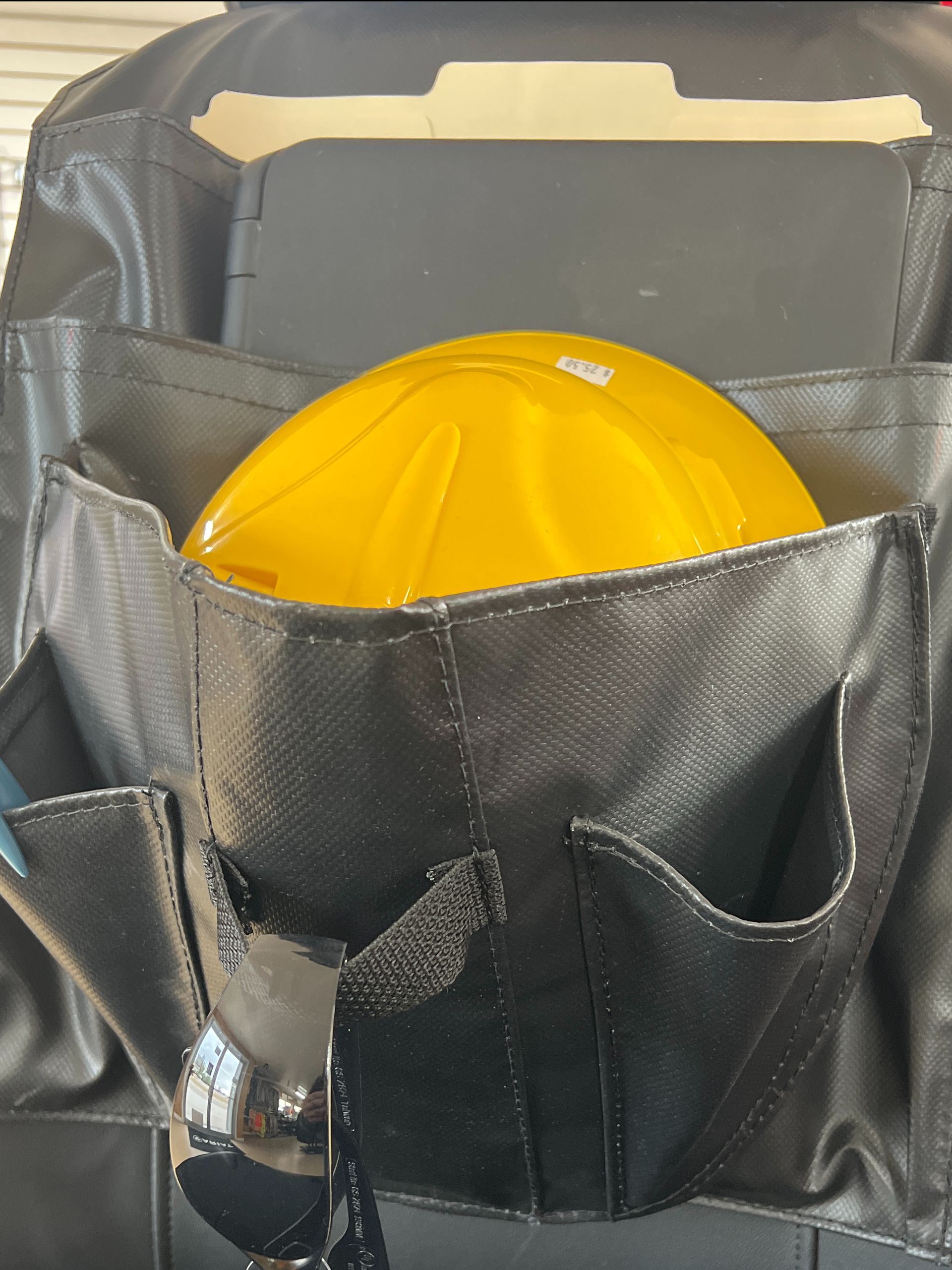 Black tool pouch holding a yellow hard hat with a flashlight clipped to the front pocket