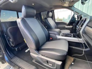 Front interior of a vehicle with black and gray leather seats and a center console, seen from the open door
