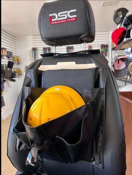 Yellow hard hat stored in a black seat-back organizer on a chair with a DSC headrest cover