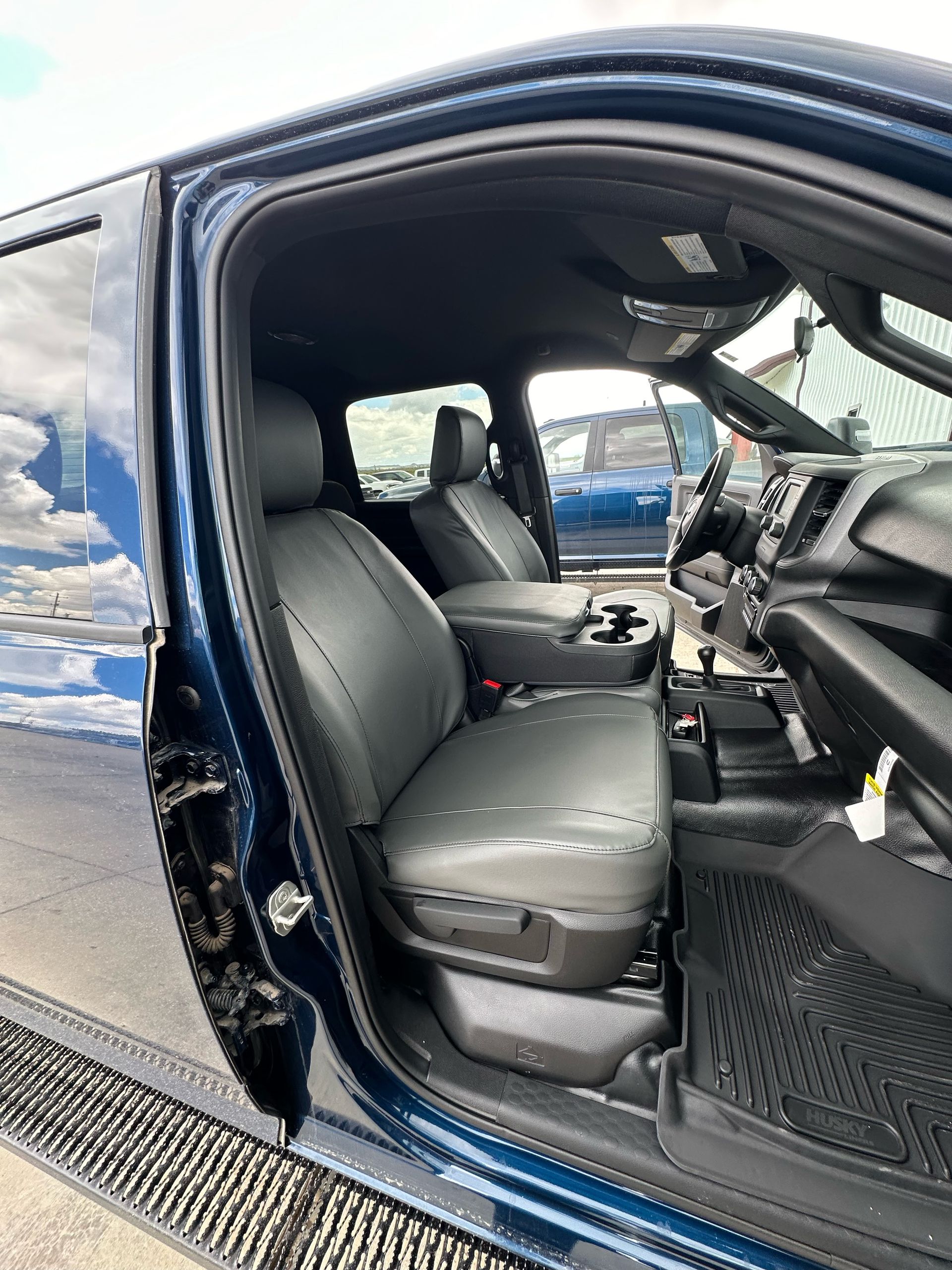 Open car door showing black leather seats and steering wheel inside a dark blue vehicle.