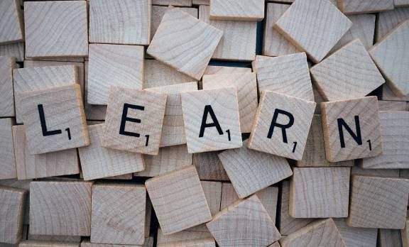 The word learn is written on wooden scrabble tiles.