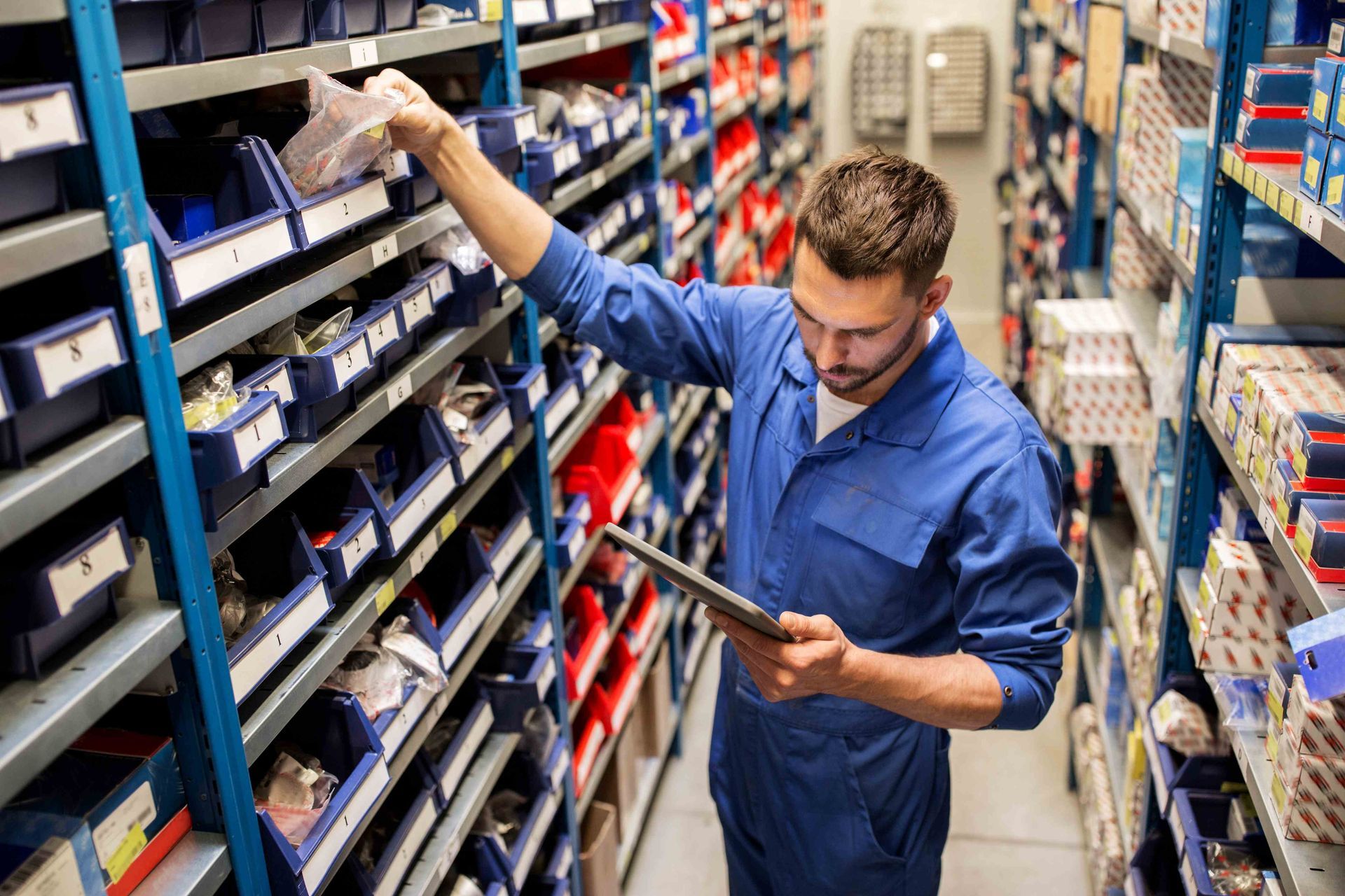 An auto mechanic or smith with a tablet at a car parts shop. An auto mechanic or smith with a tablet at a car parts shop.