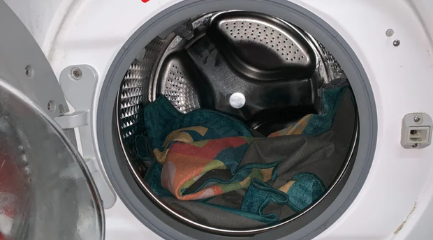 Open front-loading washer with colorful clothes inside the drum