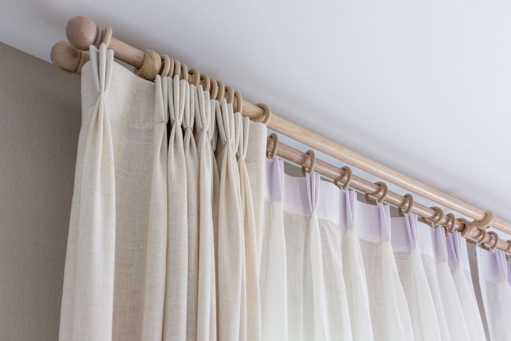 A Pair of White Curtains Hanging From a Wooden Curtain Rod — TT Shutters & Shading In Ocean Shores, NSW