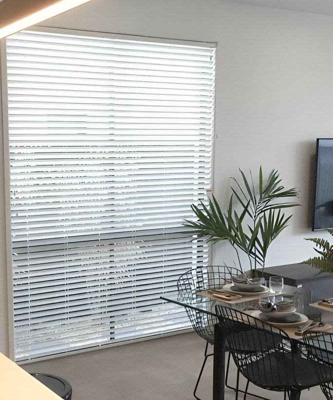 A Dining Room With a Table and Chairs in Front of a Window With Blinds — TT Shutters & Shading In Murwillumbah, NSW