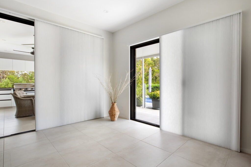 An Empty Room With White Blinds and a Vase of Flowers on the Floor — TT Shutters & Shading In Ballina, NSW