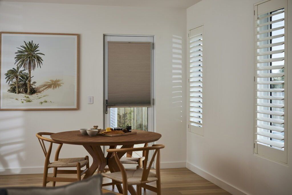 A Dining Room With a Table and Chairs and Shutters on the Windows — TT Shutters & Shading In Ballina, NSW